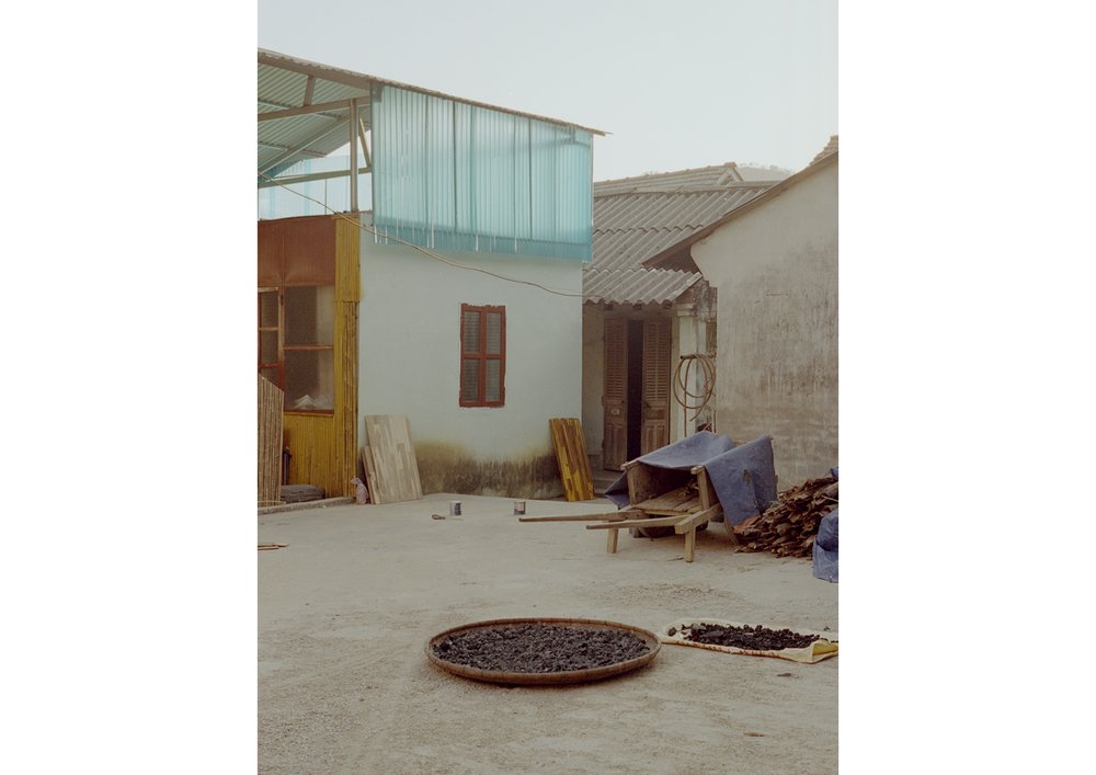 Exterior daytime shot showcasing a rural scene with residential architecture, a round tray of dark material, and subdued lighting.