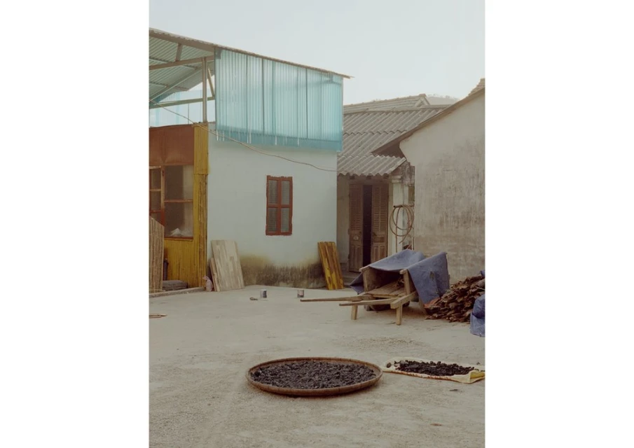 Exterior daytime shot showcasing a rural scene with residential architecture, a round tray of dark material, and subdued lighting.
