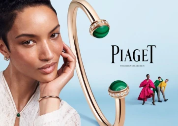 Close-up of a woman wearing jewellery alongside a large gold and malachite Piaget Possession bracelet against a blue background