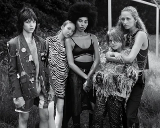 Monochrome group portrait of five models with diverse styles posing outdoors against foliage.
