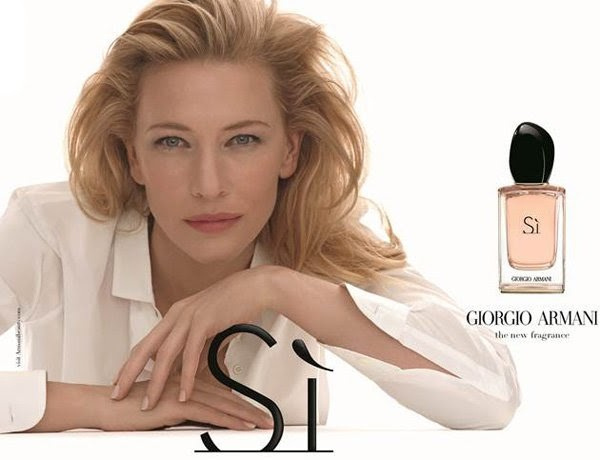 Elegant beauty shot featuring a blonde adult woman with a bottle of perfume and the 'Si' logo, set against a clean, bright background.