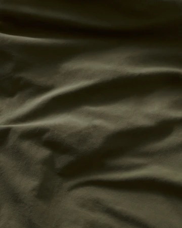 Close-up of wrinkled green fabric with a subtle sheen, showing depth and texture, ideal for backgrounds or material studies.