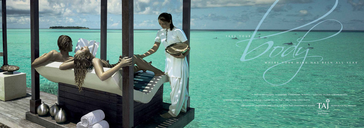 Couple receiving spa treatment at ocean-front resort. Woman in white uniform attends to lounging clients against turquoise water backdrop.