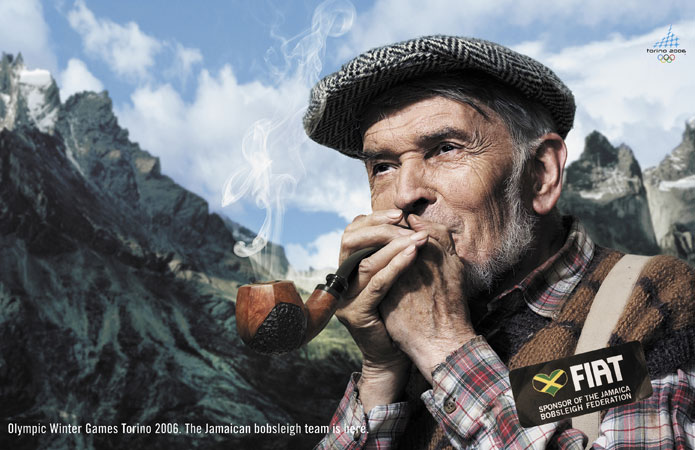Elderly man in cap smoking pipe against mountain backdrop in ad for Olympic Winter Games Torino 2006 featuring Jamaica bobsleigh team sponsor.