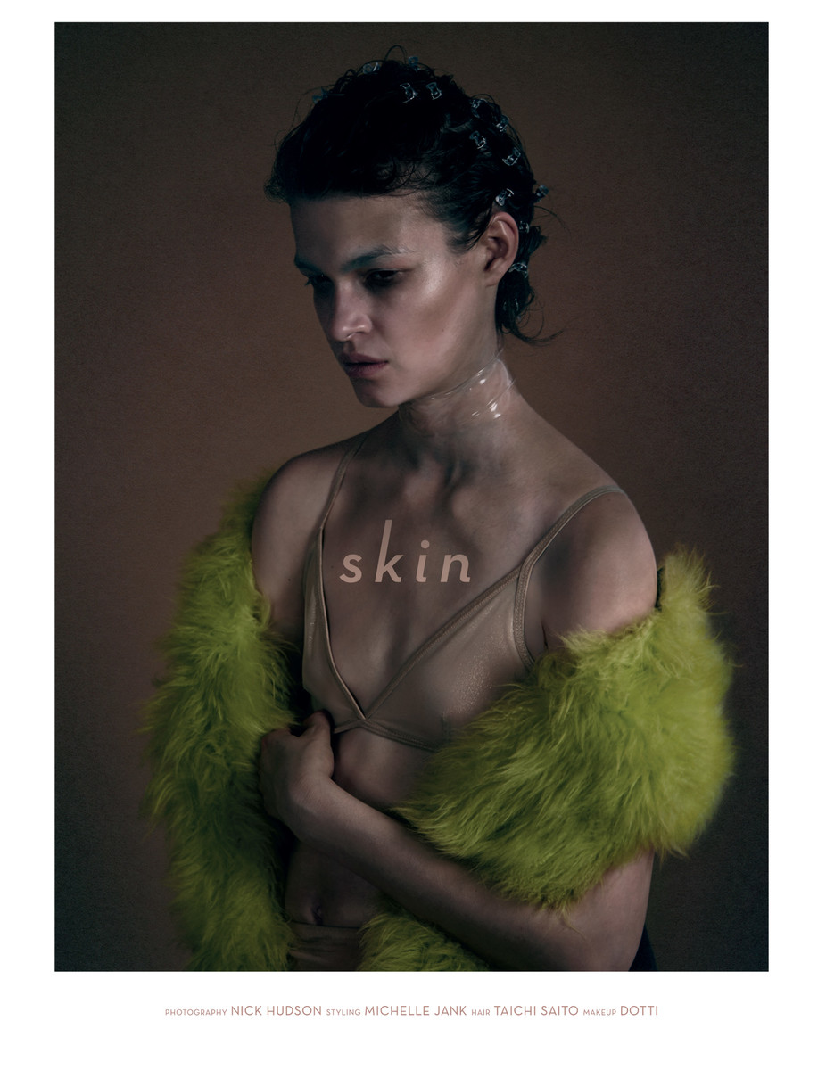 Woman poses with a furry stole in a studio shot, focusing on the model's skin, fair complexion, and fashion-forward presentation, for beauty or fashion.