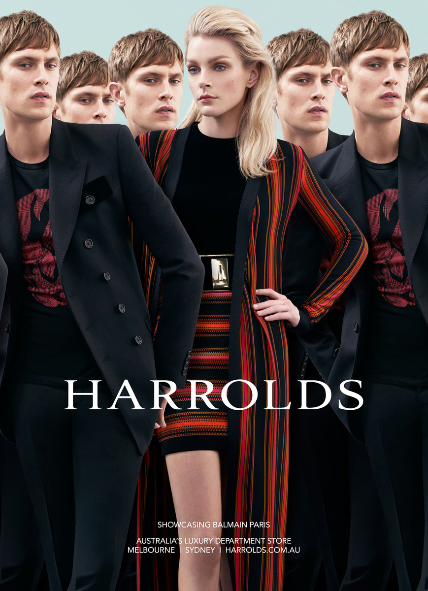 Fashion editorial shot of a woman in a black and red striped outfit surrounded by men in black suits for a Harrolds ad campaign.
