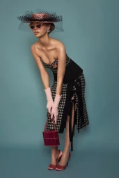 Model in houndstooth dress, pink hat with veil, pink gloves, and holding a small handbag against a solid teal background