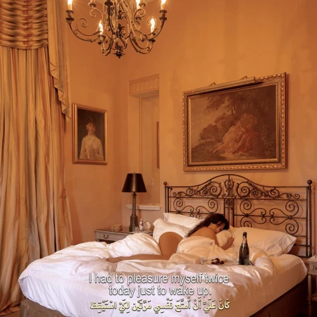 A woman lying in an ornate wrought iron bed in a warm-toned bedroom with draped curtains, framed art, and a chandelier.