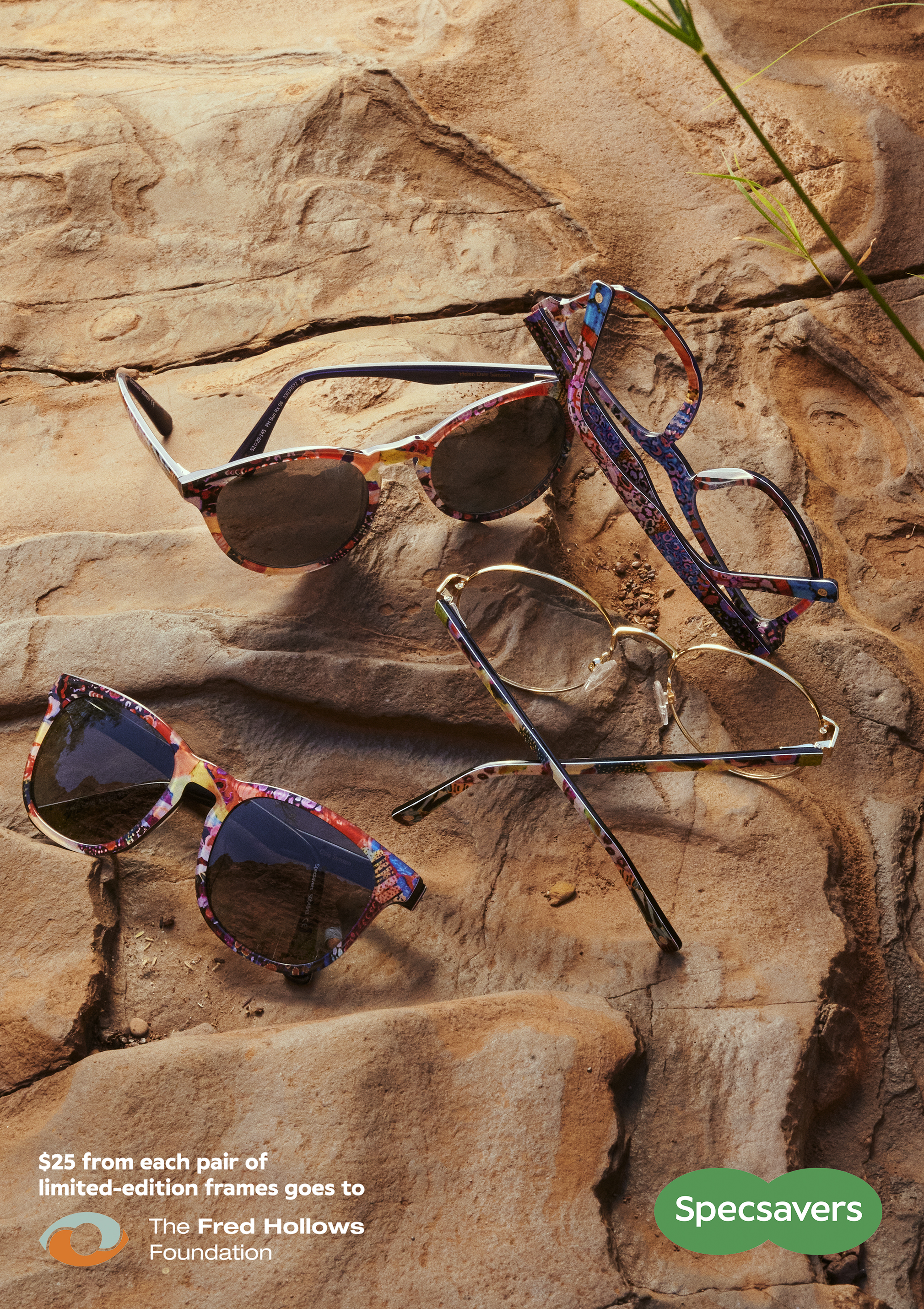 Three pairs of colorful, patterned eyeglasses are arranged on a tan rock surface in a close-up studio product shot for eyewear advertising.