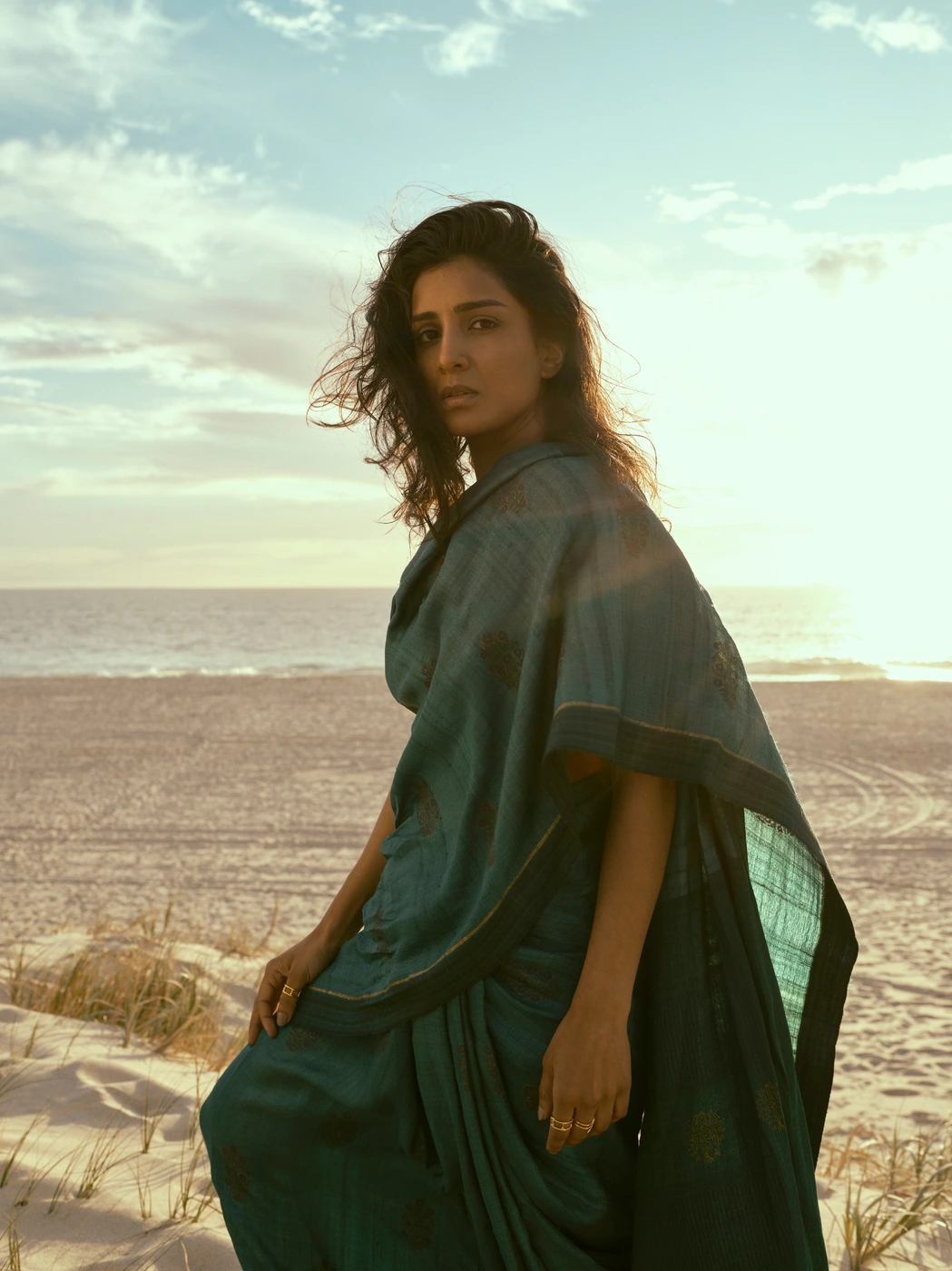 Woman in dark teal sari standing on a sandy beach at sunset by photographer Mauro Palmieri