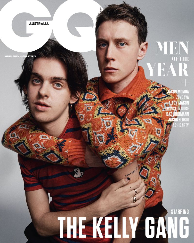 GQ Australia magazine cover featuring two adult men in a close-up studio portrait with orange and brown patterned knitwear, rings, and dark hair.
