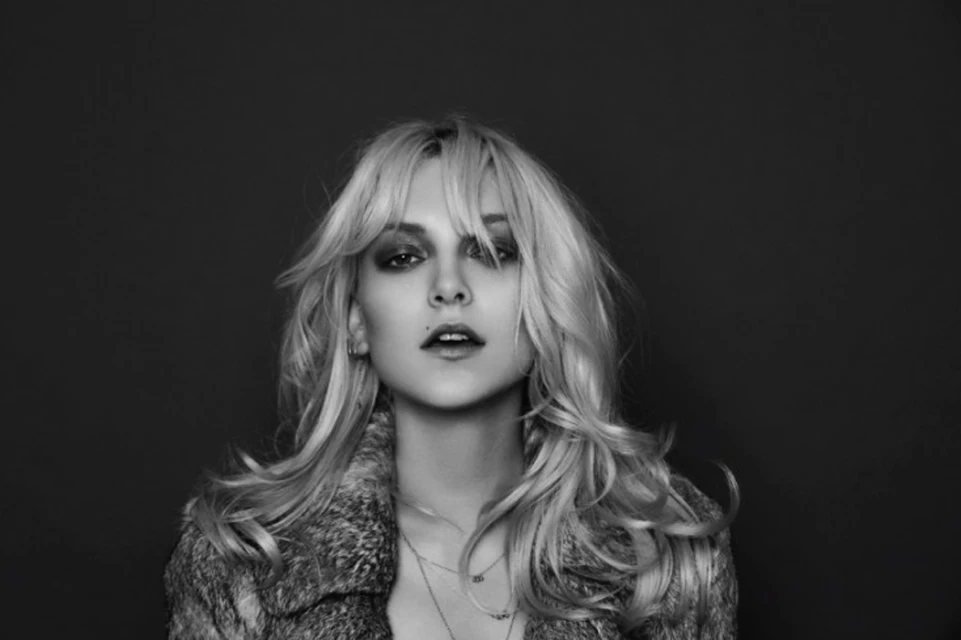 Black and white portrait of an adult female with blonde hair, wearing a fur coat, against a dark background.