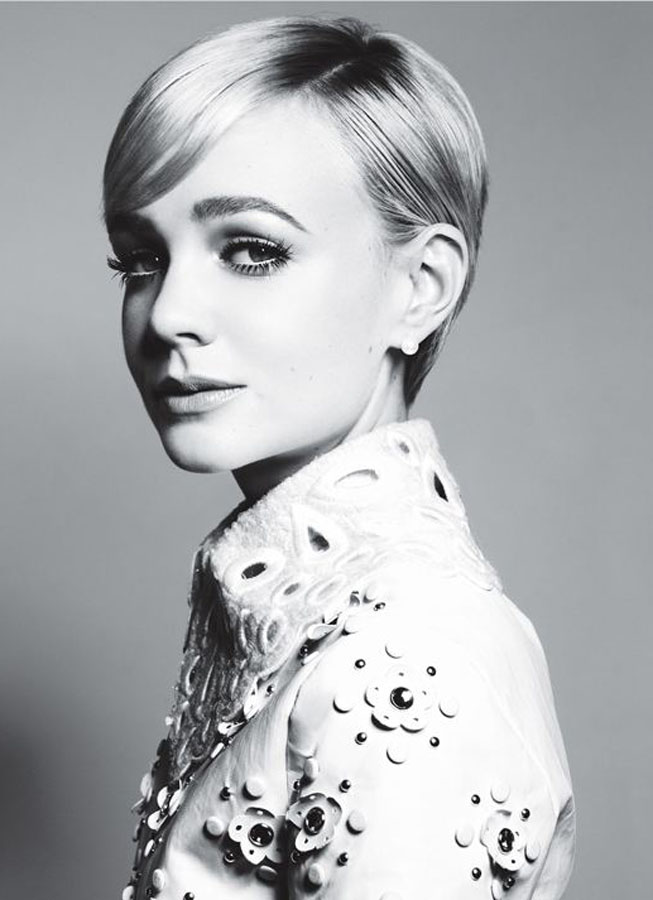 Monochrome portrait of a woman with short, light hair and a collared jacket adorned with floral embellishments in a studio setting.