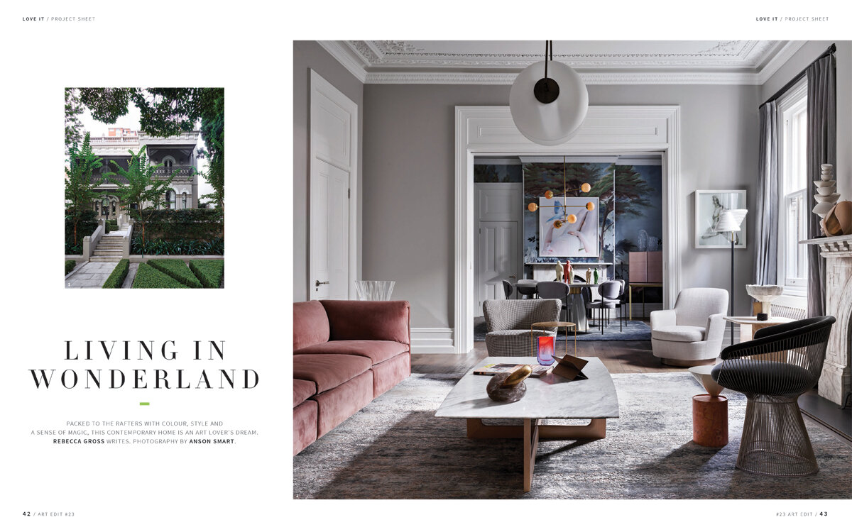 Interior view of a living room with a pink sofa, marble coffee table, neutral-toned chairs, and abstract art in a grey-walled room.