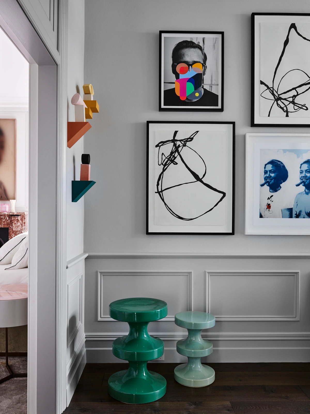 Interior styling by Claire Delmar featuring two green ceramic stools against a grey wall with art prints