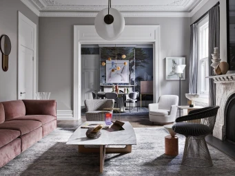 A sophisticated living room with a pink velvet sofa, white marble coffee table, modern armchairs, and a view into a dining area.