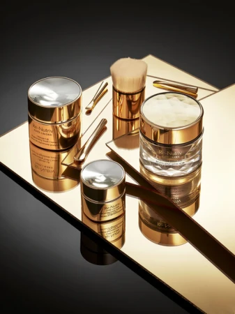 Still life shot of Re-Nutriv Ultimate Diamond Transformative skincare products by Estee Lauder in gold and black on a mirror.