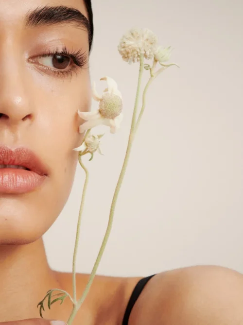 Close-up portrait of a woman holding delicate white wildflowers near her face, styled by Anna Vidovic in Sydney.