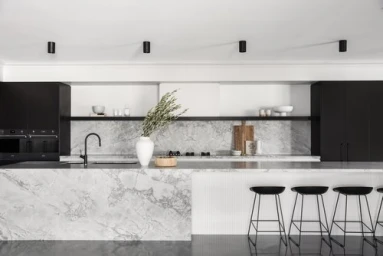 Modern minimalist kitchen interior featuring marble island bench and black bar stools styled by Rory James Carter