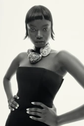 Black woman wearing a strapless black dress and statement necklace with short fringe hair by hair stylist Alan White