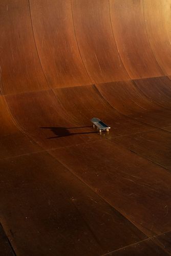 Skateboard on a wooden ramp in a skatepark, showcasing the sport and architectural design of the skatepark, set against a neutral background.