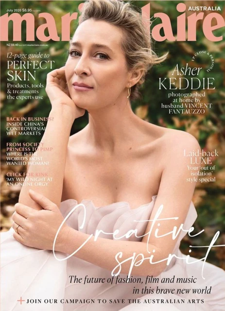 Asher Keddie graces the cover of Marie Claire Australia, July 2020 issue. She wears a white dress and poses against a leafy background.