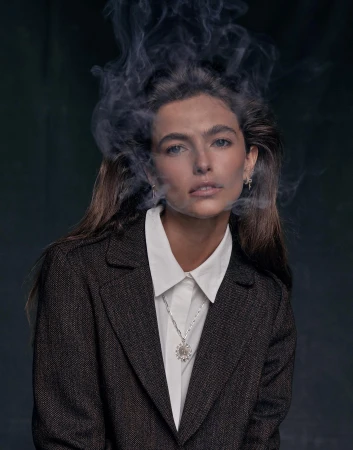 Woman in a dark blazer and white collared shirt with wisps of smoke swirling around her head