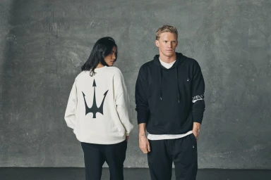 Two models wearing casual apparel against a grey textured concrete wall, styled by Tessa Law.