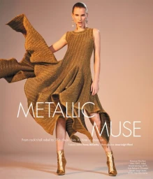 Model in metallic gold dress with flared skirt posing in studio with gold boots and statement earrings