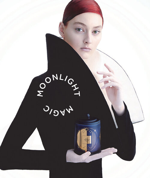Woman in black dress with a large collar holds a navy blue candle jar. White text reads 'Moonlight Magic' against a white background.