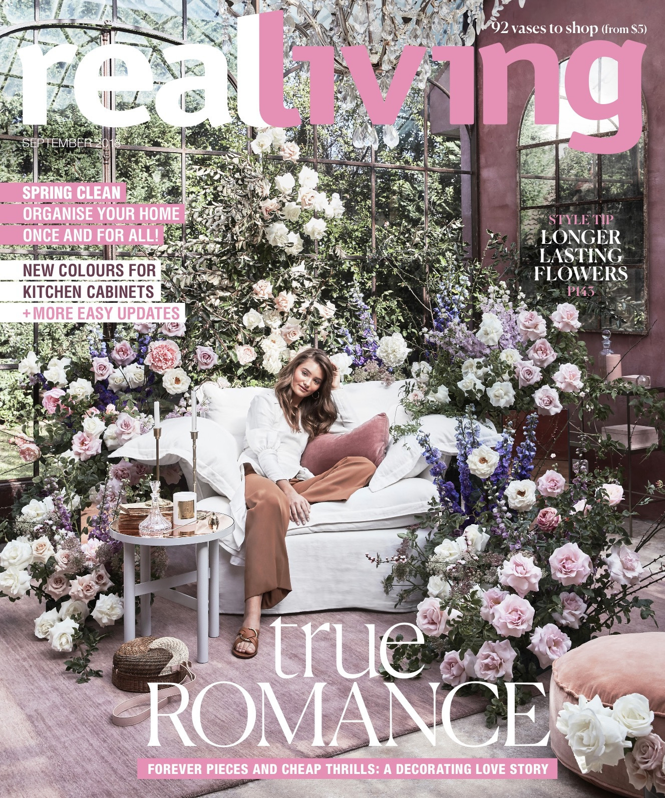 Magazine cover of Real Living with a woman sitting on a couch surrounded by flowers, promoting spring cleaning, kitchen cabinets, and romance.