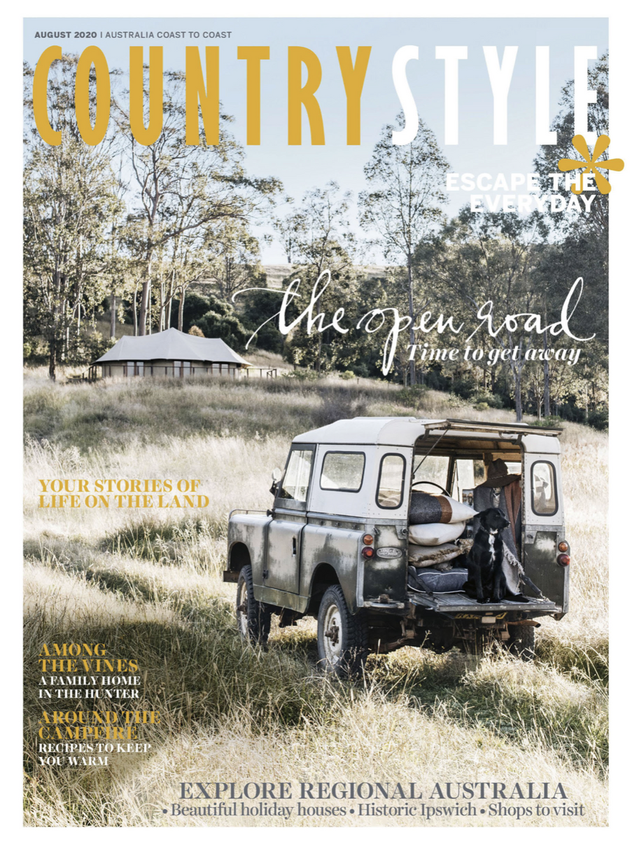 Country Style magazine cover featuring a vintage SUV parked in a grassy field with a black dog in the back, surrounded by rural scenery.