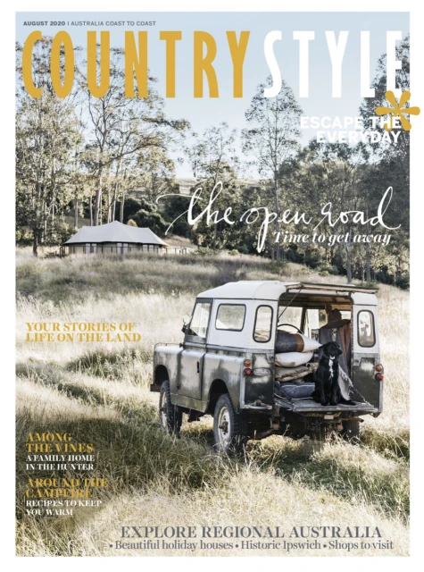 Country Style magazine cover featuring a vintage SUV parked in a grassy field with a black dog in the back, surrounded by rural scenery.
