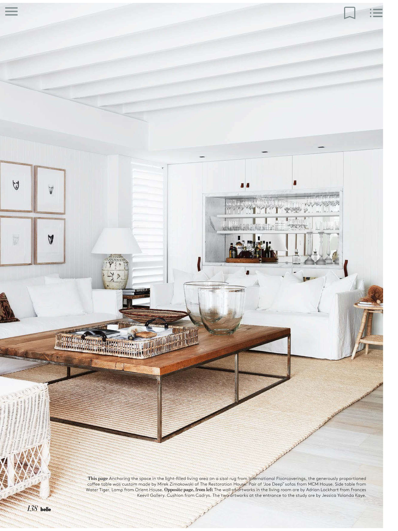 Bright living room interior with white sofas, wooden coffee table, and a woven rug, creating a cozy and elegant home space.
