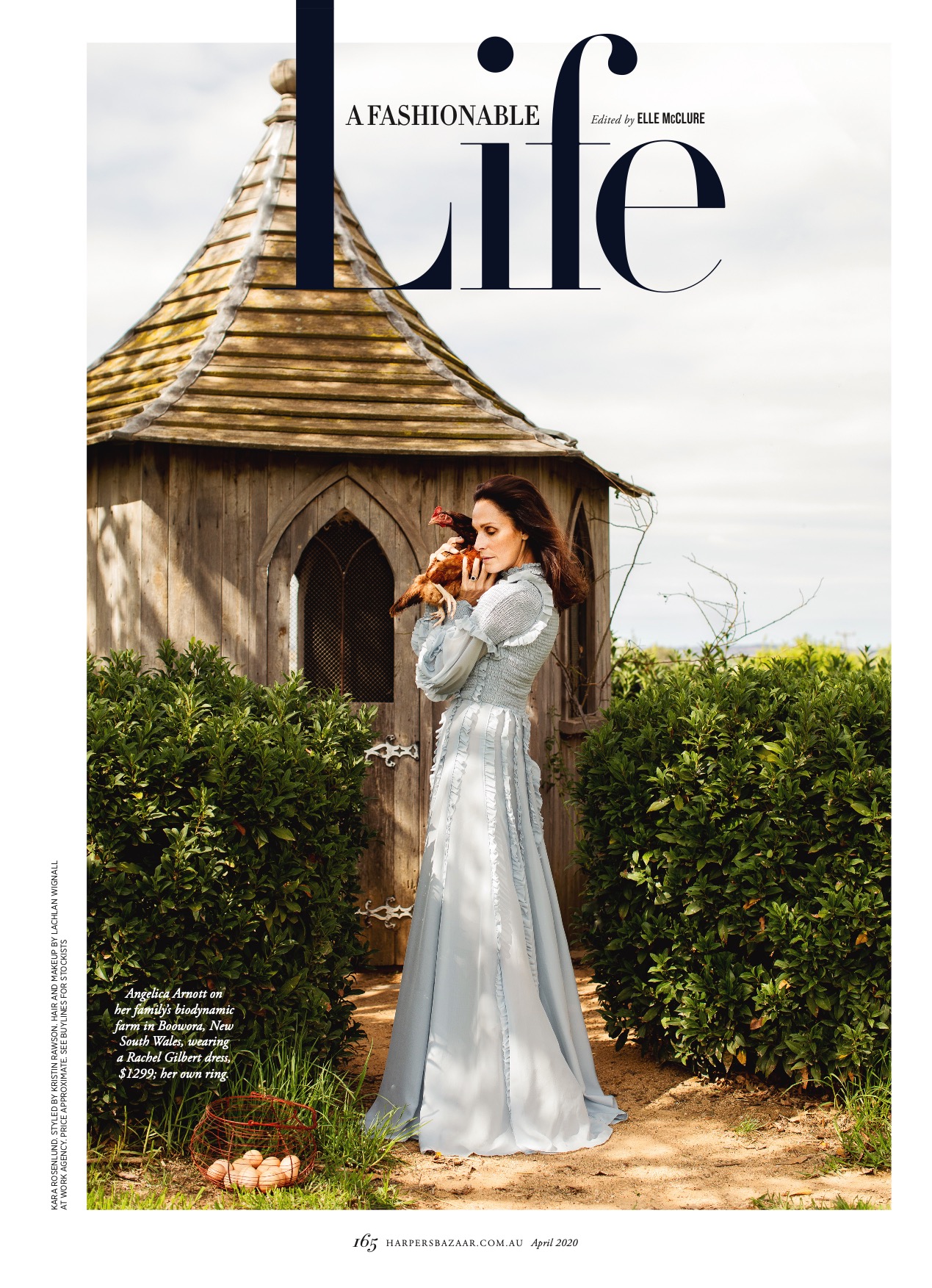 Magazine cover featuring a woman in a blue dress holding a chicken, posing in a garden with a small wooden building in the background.