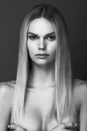 Black and white portrait of a fair-skinned woman with long blonde hair, posing in front of a dark gray background.