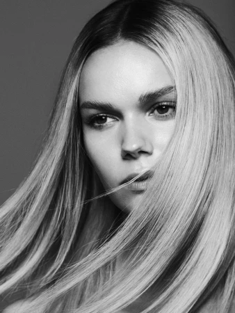 Monochrome portrait of a woman with long blonde hair partially covering her face, photographed by Rayan Ayash.