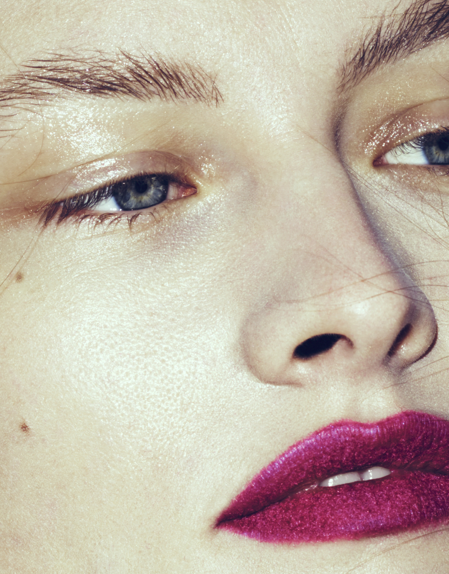 Close-up portrait of a woman with vibrant magenta lips and textured skin by Rayan Ayash