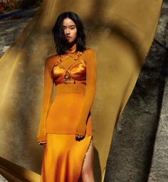 Model in orange turtleneck and satin slip skirt wearing harness straps by Rayan Ayash