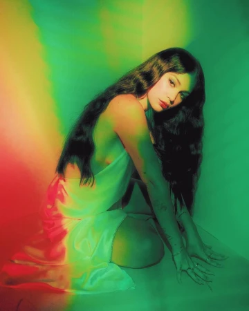 Kneeling woman with long dark hair wearing a light satin dress under vibrant green and red lighting