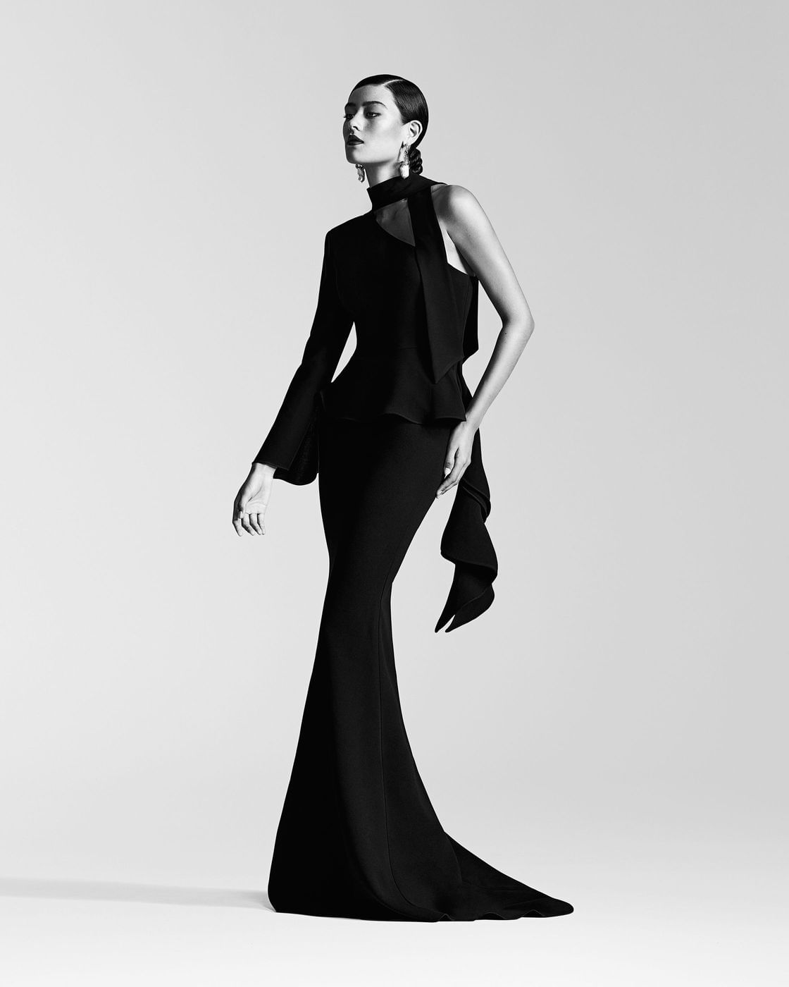 Monochrome fashion portrait of a woman in a black gown against a seamless white background