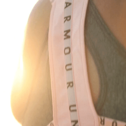 Profile shot of woman with hair in ponytail on beach in sunlight looking towards water; fitness and outdoor lifestyle scene.