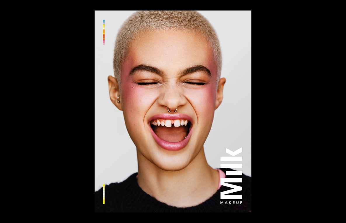 Close-up studio shot of an adult female model with pink blush and short hair laughing, showcasing beauty and makeup products.