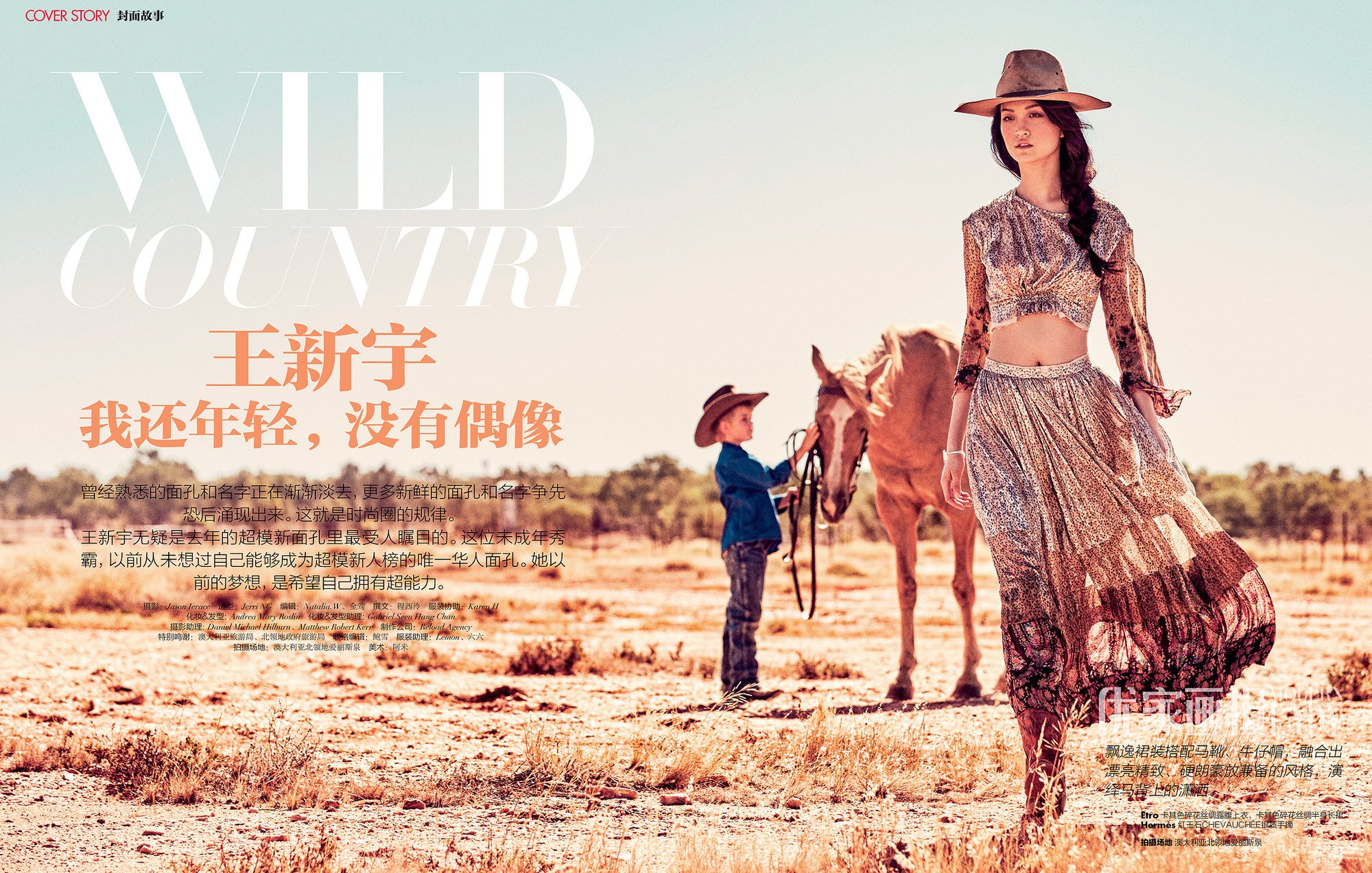 A woman in a flowing skirt and crop top stands near a horse and child wearing a cowboy hat in a sunlit, arid landscape, fashion editorial.