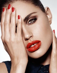 Close-up beauty portrait of a woman with vibrant red lipstick and matching red nail polish, photographed by Jason Ierace.