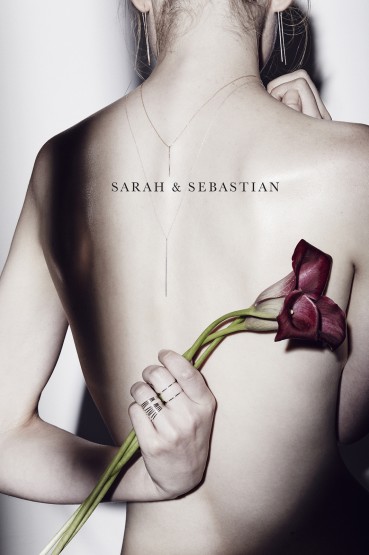 Back view of an adult woman with jewelry holding tulips, captured in a studio setting with soft lighting.