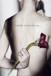 Close-up back portrait of a woman wearing delicate layered necklaces and rings, holding dark calla lily flowers behind her back.