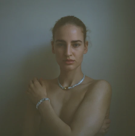 Portrait of a woman wearing a diamond necklace and bracelet against a neutral grey studio background