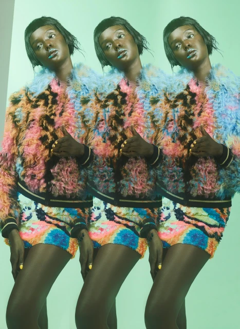 Fashion shot features three identical African American women in colorful faux fur jackets and sequined shorts against a light green background.