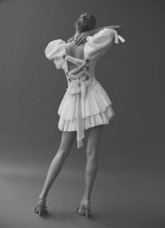 Model in white lace-up back dress posing against a grey seamless studio background shot by Monica Russell.